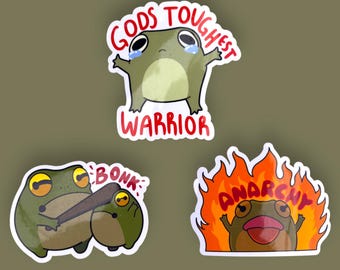 May include: Three frog stickers with different designs. The first sticker shows a green frog with the text "Gods Toughest Warrior". The second sticker shows two frogs with a baseball bat and the text "Bonk". The third sticker shows a frog in flames with the text "Anarchy".