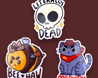 May include: Three sticker designs featuring a bee, a cat, and a skull. The bee is wearing a cowboy hat and has the text "Bee Haw" below it. The cat is wearing a red bandana and a cowboy hat and has the text "Meowdy" below it. The skull has the text "Literally Dead" around it.