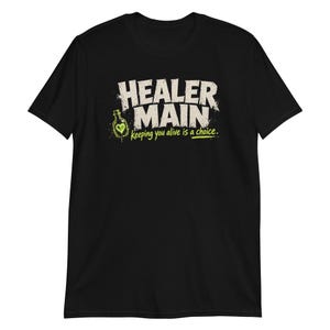 Könnte beinhalten: Ein schwarzes Kurzarm-T-Shirt mit dem weißen Schriftzug HEALER MAIN und einer kleinen Grafik einer grünen Zaubertrankflasche mit Herzsymbol. Unter dem Text steht der Satz keeping you alive is a choice in hellem Limettengrün gedruckt.
