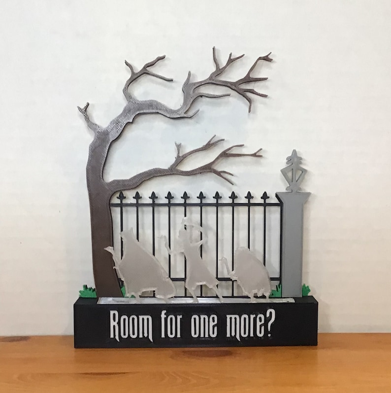 May include: A 3D printed Halloween decoration featuring a black iron gate with a spooky tree and three ghostly figures. The base of the decoration has a black background with the text "Room for one more?"