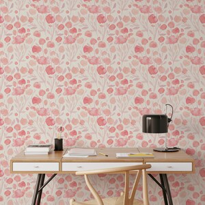May include: A light wood desk with two drawers and a black metal frame. A chair with a woven seat and a black lamp are in front of the desk. The wall behind the desk is covered in pink floral wallpaper.