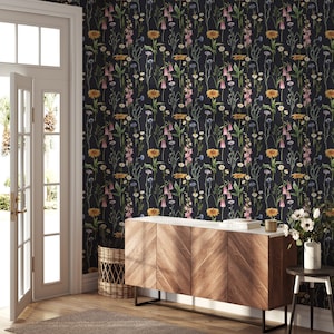 May include: A dark gray wallpaper with a floral pattern featuring pink, yellow, and white flowers. The wallpaper is displayed on a wall in a room with a wooden cabinet and a wicker basket.