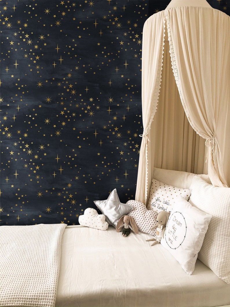 K&ouml;nnte beinhalten: Ein wei&szlig;es Himmelbett mit einer wei&szlig;en Decke und Kissen. Die Wand hinter dem Bett ist dunkelblau mit goldenen Sternen. Die Kissen haben den Text "You are so loved" und "Dream big little one".