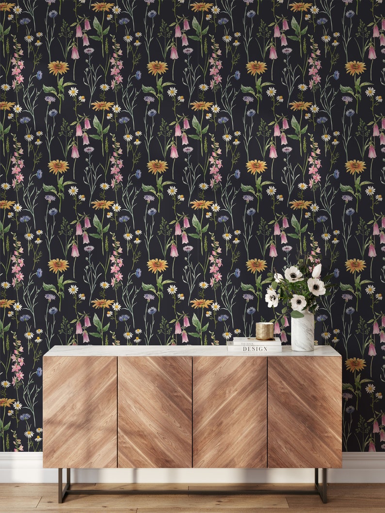 May include: A wooden cabinet with three drawers and a black marble top. The cabinet is in front of a black wallpaper with a floral pattern featuring pink, yellow, and white flowers.