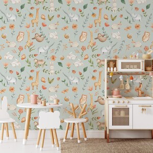K&ouml;nnte beinhalten: Eine hellblaue Tapete mit einem sich wiederholenden Muster aus Tieren und Blumen. Zu den Tieren geh&ouml;ren Giraffen, Elefanten, Eulen, Faultiere und Kaninchen. Die Blumen sind in Orange-, Rosa- und Gelbt&ouml;nen gehalten. Die Tapete ist in einem Raum mit einer wei&szlig;en Spielk&uuml;che und drei Holzst&uuml;hlen zu sehen.