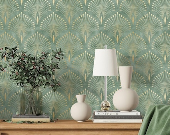 May include: A green and gold wallpaper with a geometric pattern of stylized peacock feathers. The wallpaper is displayed in a room with a wooden table, two white ceramic vases, a white lamp with a silver base, and a stack of books.