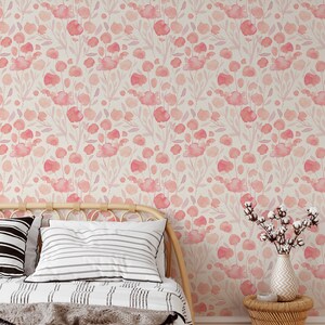 May include: A bedroom with a bed featuring a white and black striped duvet and a throw blanket. The bed is against a wall with a pink floral wallpaper. A small side table with a vase of cotton flowers is next to the bed.