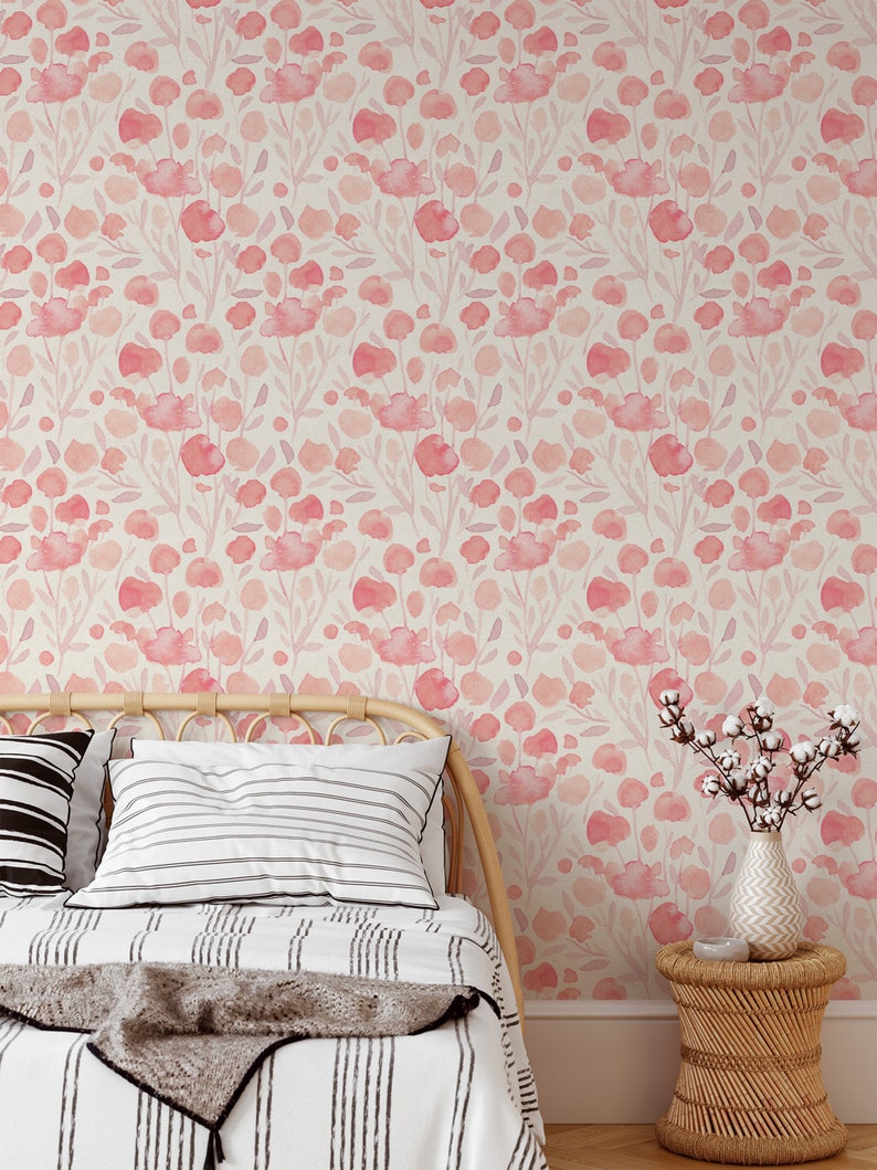 May include: A bedroom with a bed featuring a white and black striped duvet and a throw blanket. The bed is against a wall with a pink floral wallpaper. A small side table with a vase of cotton flowers is next to the bed.