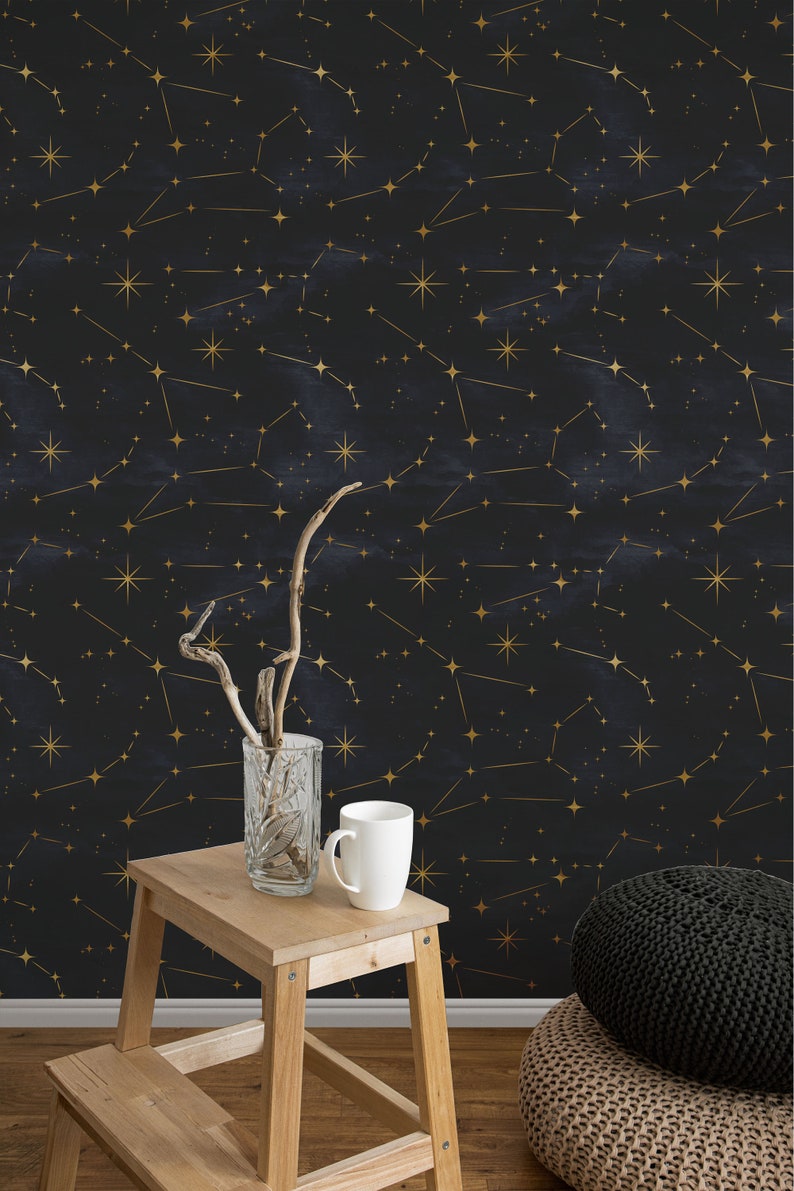 Pu&ograve; includere: Una carta da parati blu scuro con un motivo a costellazione dorata. In primo piano uno sgabello di legno e due pouf intrecciati.