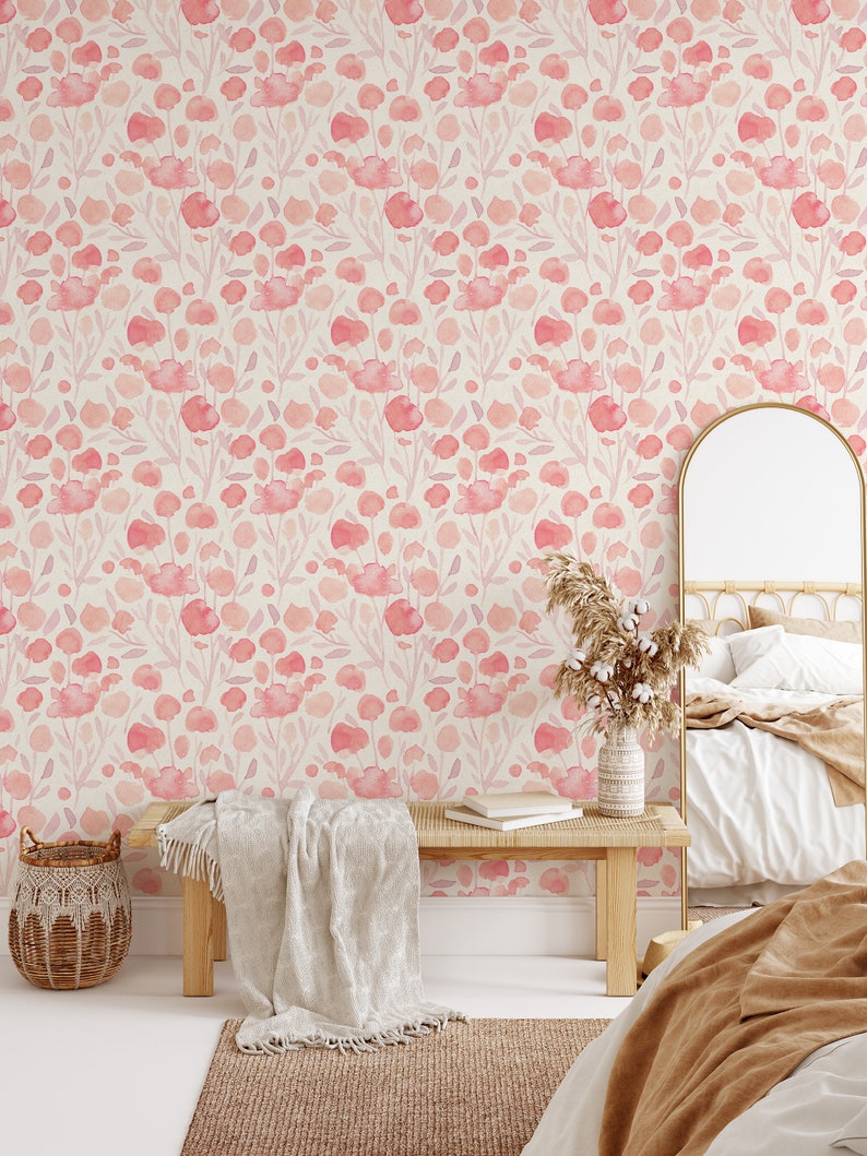 May include: A bedroom interior with a light pink floral wallpaper featuring a watercolor design. The room has a wooden bench with a white throw blanket, a wicker basket, a mirror, and a bed with a brown throw blanket.