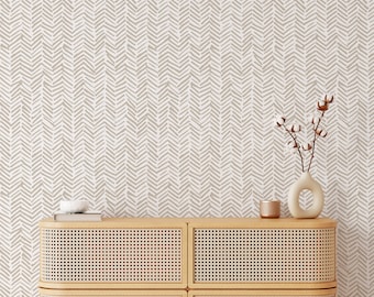 May include: A light brown patterned wallpaper with a woven rattan cabinet with four drawers. The cabinet has a rounded front and sits on four legs. A small white ceramic bowl and a vase with dried cotton flowers are on top of the cabinet.