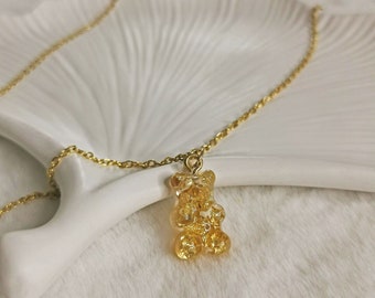 May include: A gold chain necklace with a gold gummy bear pendant.