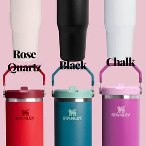 May include: A collection of Stanley brand insulated tumblers in various colors, including Rose Quartz, Black, Chalk, Chili, Coastal Teal, and Dark Blossom. Each tumbler features a handle and the Stanley logo.