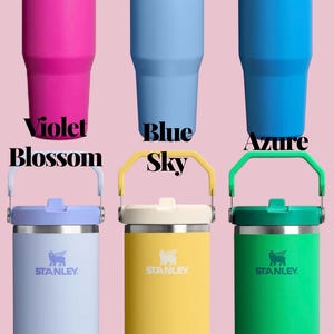 May include: A collection of Stanley tumblers in various colors, including violet, blue, azure, dew drop, daffodil, and meadow green. Each tumbler has a handle and the Stanley logo. The text "Violet Blossom", "Blue Sky", "Azure", "Dew Drop", "Daffodil", and "Meadow" are displayed.