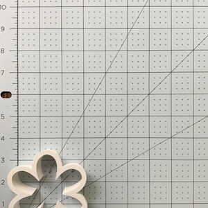 May include: White plastic cookie cutter shaped like a five-petal flower. The cutter is 2 inches wide and 2 inches tall.
