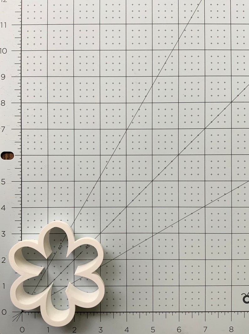 May include: White plastic cookie cutter shaped like a five-petal flower. The cutter is 2 inches wide and 2 inches tall.