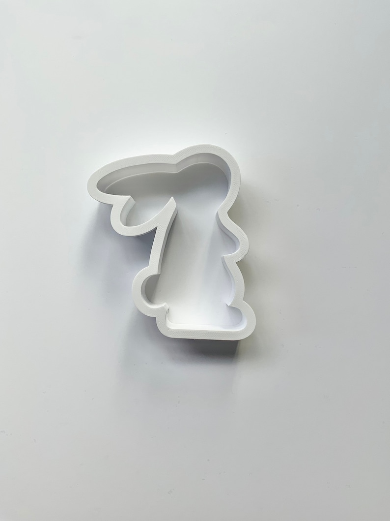 May include: White plastic cookie cutter shaped like a bunny rabbit.
