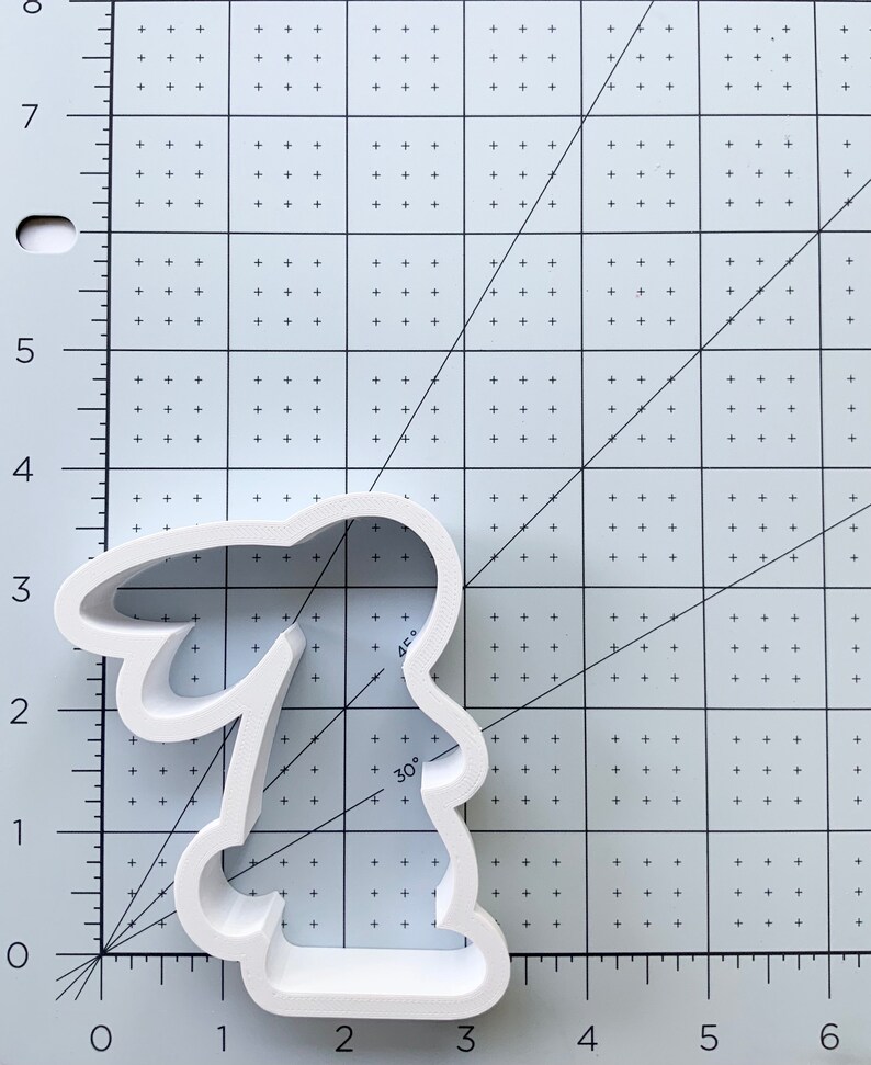 May include: White plastic cookie cutter shaped like a bunny rabbit. The cutter is approximately 3 inches tall and 2 inches wide.