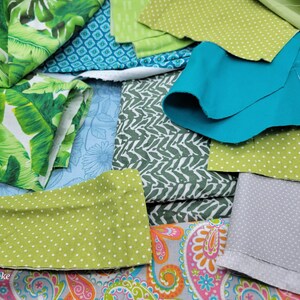Op de afbeelding: Een assortiment van stoffenresten in verschillende patronen en kleuren, waaronder groen, blauw, wit en roze. De stoffen zijn in een stapel gerangschikt, waarbij sommige elkaar overlappen.
