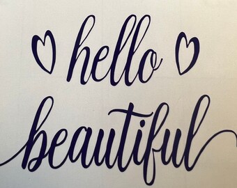 May include: A white background with the words "hello beautiful" in dark blue cursive script. Two heart shapes are above the word "hello". The image is a decorative design.