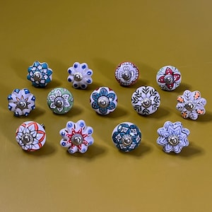 May include: Assortment of 12 ceramic drawer knobs with colorful floral patterns and silver accents. The knobs are round and have a raised design.