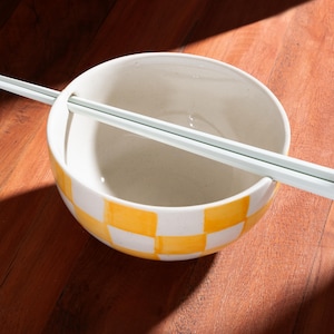 Handcrafted ceramic ramen noodle bowl with built-in chopstick holder and hand-painted yellow checkered design