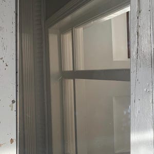 May include: A rectangular wall mirror featuring a smooth, reflective glass surface framed by two curved, light brown wooden panels at the top and bottom edges. The mirror has a clean, simple design with a polished finish on the wood accents.