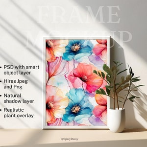 May include: A white framed art print featuring a watercolor floral design with vibrant blue, red, and orange flowers. The print is displayed on a neutral surface with a small potted plant. The image includes text: PSD with smart object layer, Hires Jpeg and Png, Natural shadow layer, and Realistic plant overlay.