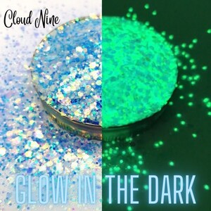 May include: A close-up of a jar of blue and white glitter that glows green in the dark. The jar is labeled "Cloud Nine".