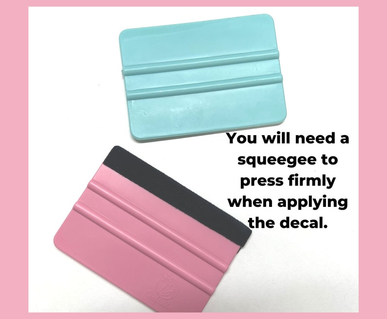 May include: Two plastic squeegees, one pink and one light blue, with black handles. The squeegees have three parallel lines on the blade. The text "You will need a squeegee to press firmly when applying the decal." is below the squeegees.