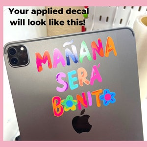 May include: A silver iPad with a colorful decal that reads "Ma&ntilde;ana ser&aacute; bonito" with a flower design.