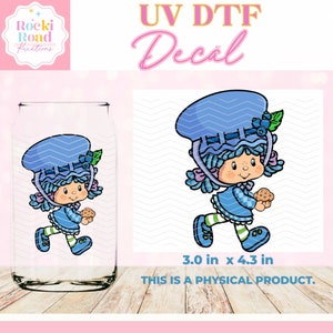 May include: A blue and white cartoon character with a blue hat and a cookie in her hand. The character is walking and has a blue and white checkered dress. The image is a UV DTF decal, 3.0 inches by 4.3 inches.