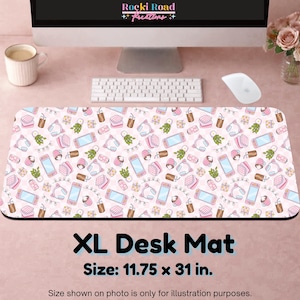 Peut inclure: Un tapis de bureau rectangulaire extra-large avec un motif répétitif de consoles de jeux, casques, plantes en pot et boissons roses et bleu clair sur fond rose pâle. Le tapis porte le texte XL Desk Mat et 11.75 x 31 in.