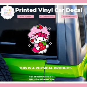 K&ouml;nnte beinhalten: Ein rosa-wei&szlig;er Autoaufkleber aus Vinyl mit einer Comicfigur, die eine Erdbeere h&auml;lt. Der Aufkleber ist mit umweltfreundlicher L&ouml;sungsmitteltinte bedruckt und wasserfest. "Rocki Road Kreations" ist oben links gedruckt. "Printed Vinyl Car Decal" ist oben in der Mitte gedruckt. "Ready to Apply", "Eco-Solvent Print" und "Water Resistant" sind oben rechts gedruckt. "This is a physical product." ist unten in der Mitte gedruckt. "Size of decal shown is for illustration purposes only." ist unten in der Mitte gedruckt.