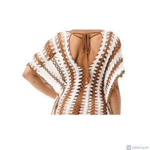 May include: A white and brown crochet cover-up with a deep V-neck and a tie at the back.