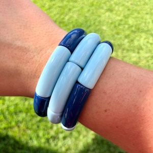 May include: A stack of blue and light blue bangle bracelets made of chunky, rounded beads.