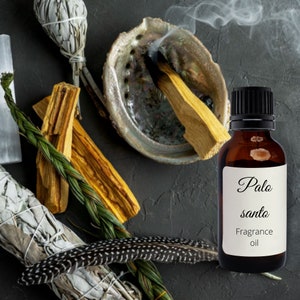 Könnte beinhalten: Eine braune Glasflasche mit Palo Santo Duftöl und einem weißen Etikett mit der Aufschrift "Palo Santo Fragrance Oil". Die Flasche steht auf einer dunkelgrauen Oberfläche, auf der ein Stück Palo Santo Holz in einer Muschel brennt.
