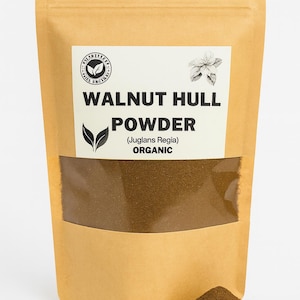 May include: A brown paper bag of walnut hull powder with a clear window, and a small pile of the powder. The bag has a white label with the words "WALNUT HULL POWDER" and "ORGANIC".