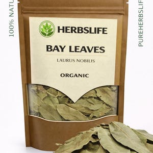 May include: A brown paper bag of bay leaves with the text "HERBSLIFE BAY LEAVES LAURUS NOBILIS ORGANIC". A pile of bay leaves is in front of the bag. The bag also has the text "100% NATURAL" and "PUREHERBSLIFE.com".