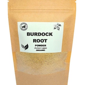 Puede incluir: Una bolsa de papel marrón con una etiqueta blanca que dice "Burdock Root Powder (Arctium Lappa) Organic". La bolsa contiene un polvo marrón claro.