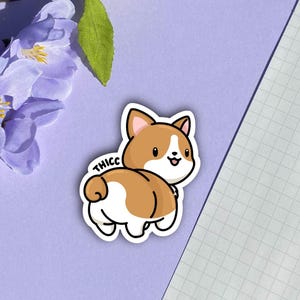 May include: A sticker of a cartoon corgi with the word "THICC" written above it. The corgi is brown and white and has a happy expression.