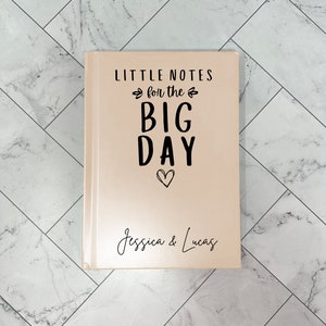 May include: A peach-colored notebook with the text "LITTLE NOTES for the BIG DAY" and a heart symbol. The names "Jessica & Lucas" are written in cursive at the bottom.