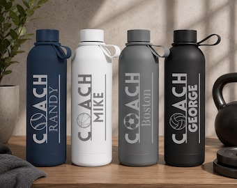 May include: Four cylindrical water bottles in navy blue, white, gray, and black, each featuring a carrying loop on the cap. The bottles are printed with the word COACH, a specific name, and a sports ball graphic including baseball, basketball, soccer, and volleyball.