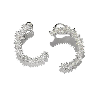 May include: A pair of silver hoop earrings with a sparkly, flower-shaped design.