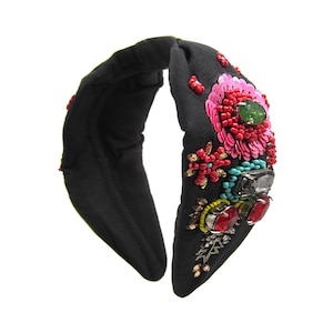 May include: Black fabric headband with a knotted design and embellished with colorful beads, sequins, and rhinestones in a floral pattern.