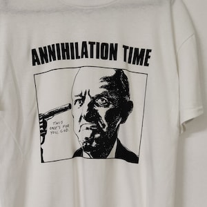 May include: White t-shirt with a black and white graphic print of a man holding a gun to his head. The text "Annihilation Time" is printed above the graphic. The text "This one's for you, God." is printed below the graphic.
