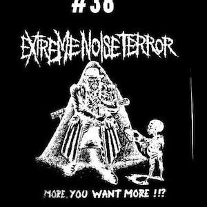 Puede incluir: Ilustraci&oacute;n en blanco y negro de un logotipo de banda, "Extreme Noise Terror", con el n&uacute;mero 38. La imagen presenta una figura con una capucha que sostiene un arma, y una figura m&aacute;s peque&ntilde;a de pie a la derecha. El texto "More, you want more!!" est&aacute; en la parte inferior de la imagen.