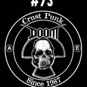 以下が含まれることがあります： ガス マスクをつけた頭蓋骨が描かれた白黒のロゴ。ロゴには「Crust Punk」と「Doom」の文字が書かれており、その下に「#73 Since 1987」の文字が書かれている。