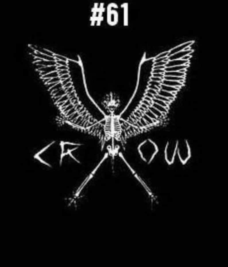 Pu&ograve; includere: Grafica in bianco e nero di un corvo scheletrico con le ali spiegate. La parola "CROW" &egrave; scritta sotto il corvo in un font stilizzato. Il numero "#61" &egrave; in cima all'immagine.