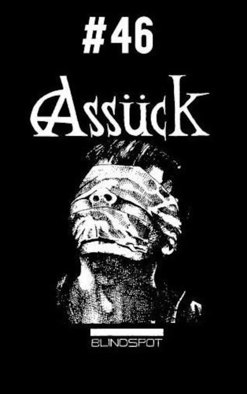Puede incluir: Dise&ntilde;o gr&aacute;fico en blanco y negro con el texto "#46 Assuck" y la palabra "Blindspot" en la parte inferior. Una persona con los ojos vendados est&aacute; en el centro del dise&ntilde;o.